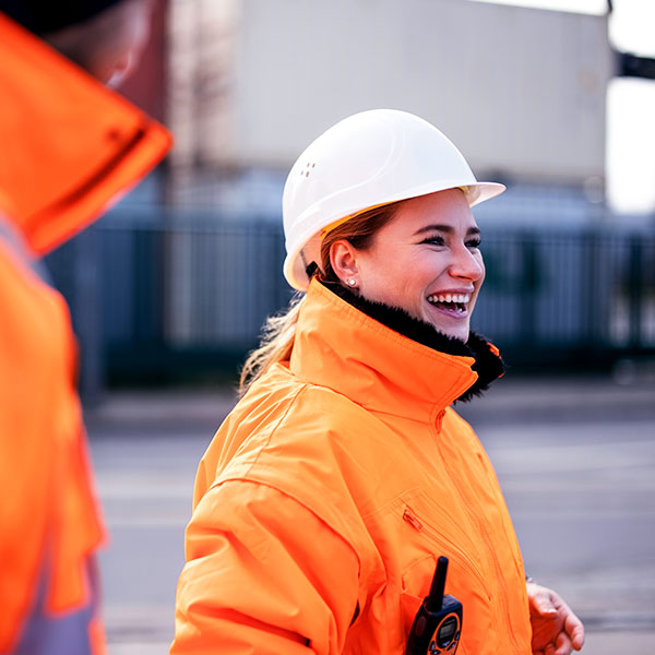 Female industrial worker orange coat averted gaze