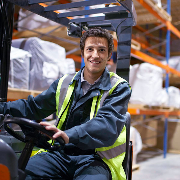 Man driving forklift in warehouse direct gaze