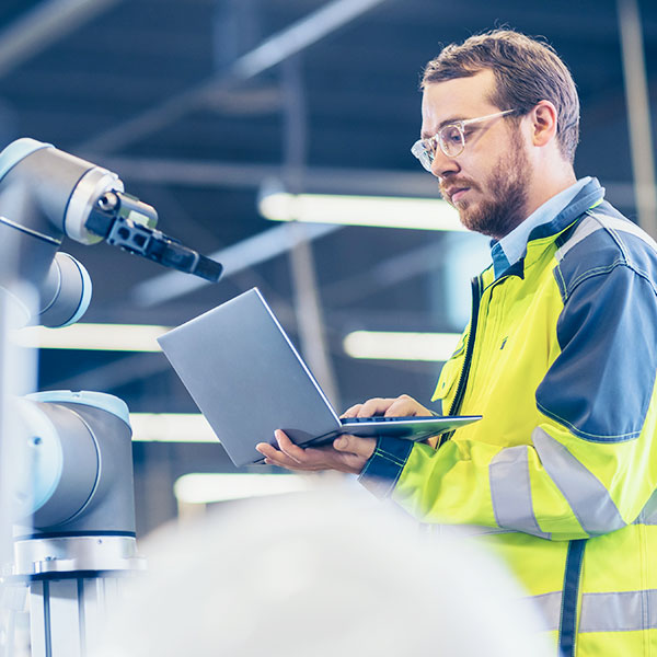 Man using laptop near machines in factory