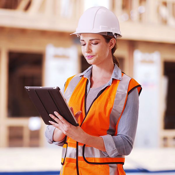 Female technician in orange vest using tablet