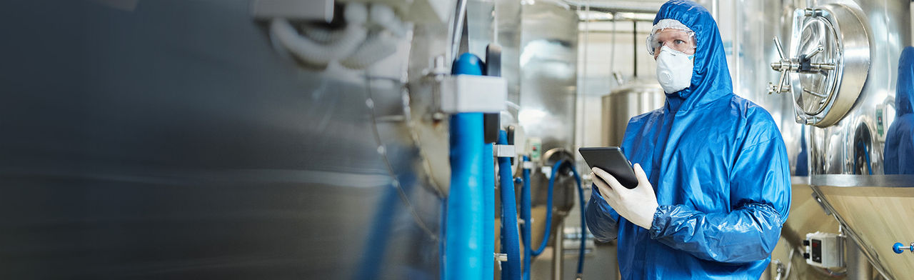 Man in protective gear inspecting industrial equipment