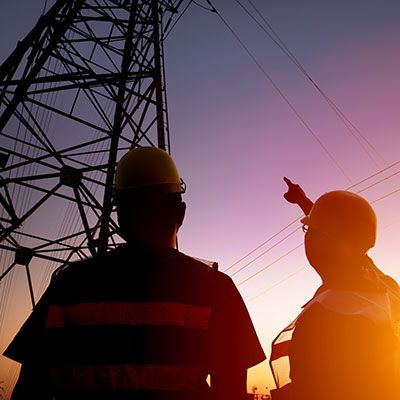 Workers near utility tower at sunset