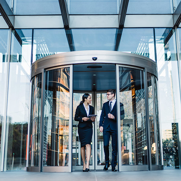 man and woman talking while walking out of round revolving doors