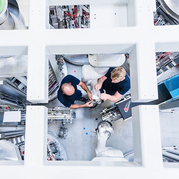 Engineers working on electrical connectors in automation factory environment.