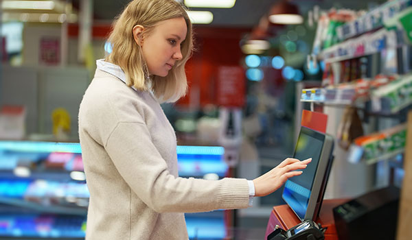 Customer using self checkout automation in retail store.