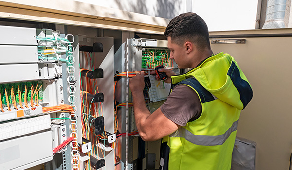 Fiber technician working on electrical panel.