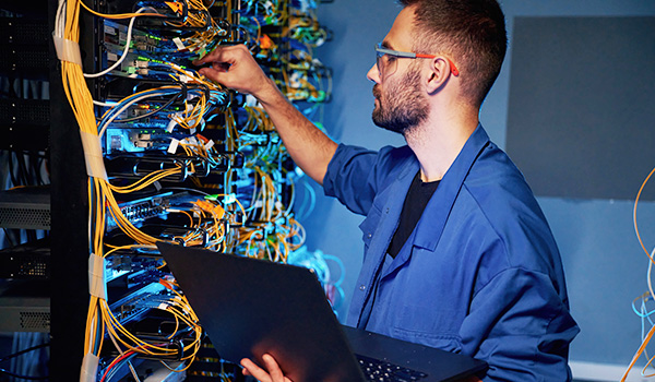 Network engineer connecting cables in server room