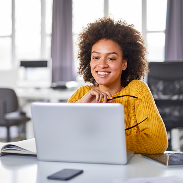 Smiling woman at desk using laptop