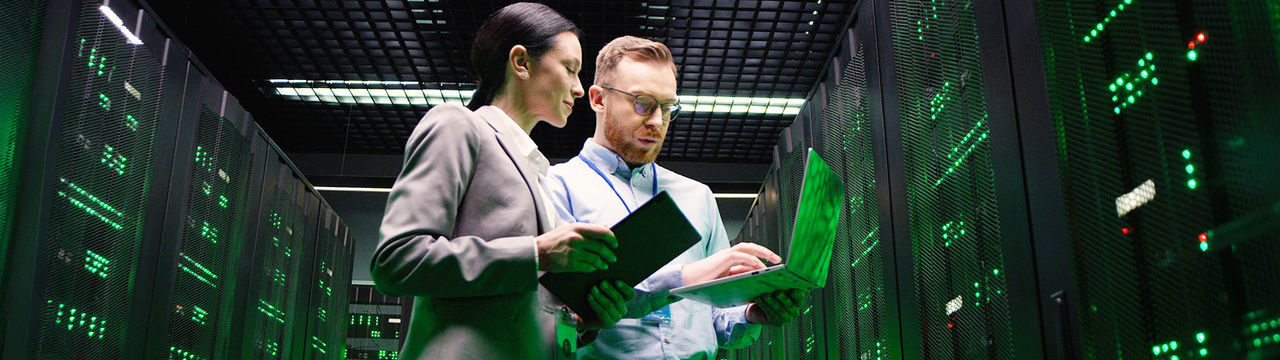 Male and female workers in modern data center with green lighting