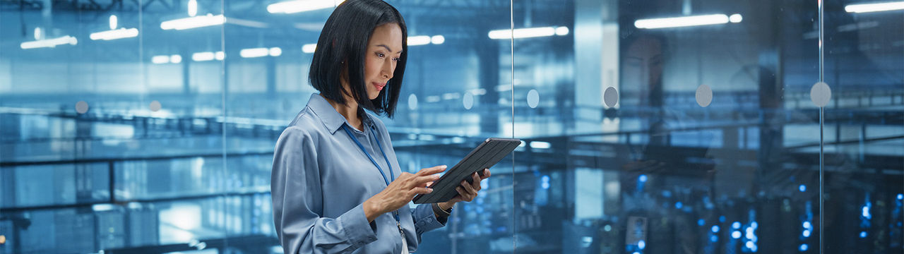 Woman using tablet above large data center