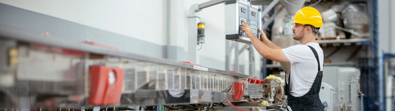 Factory worker adjusting control panel