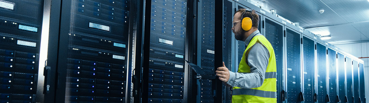 Engineer in a data center server room wearing PPE safety gear.