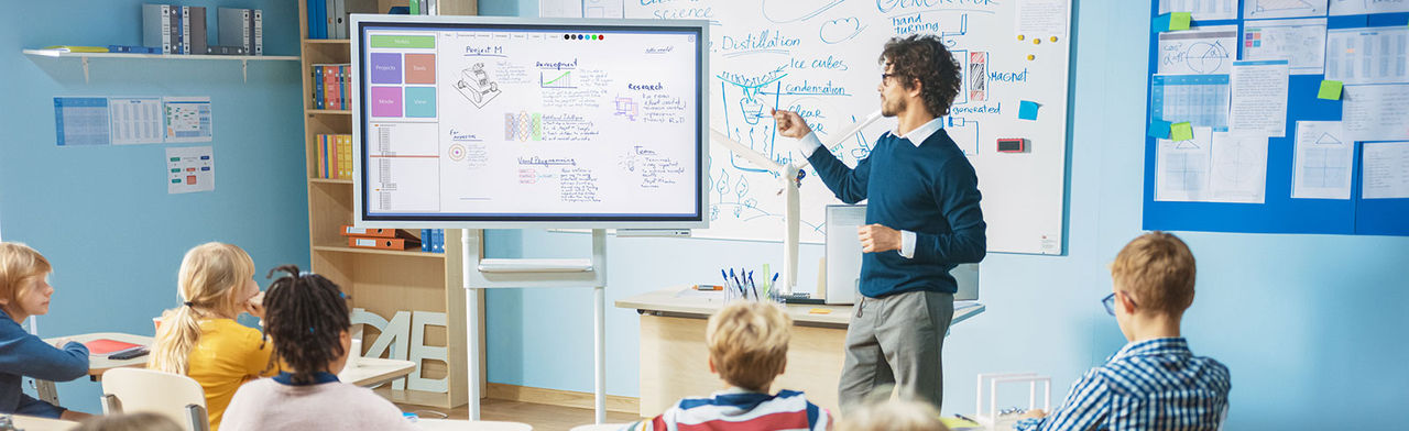 Teacher in modern school classroom using smart board technology.