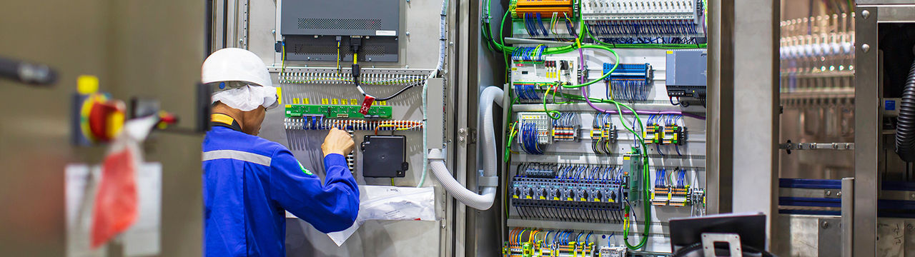 Electrician testing electrical cabling in cabinet