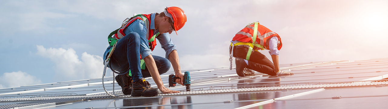 Two men installing the solar panels on roof structure