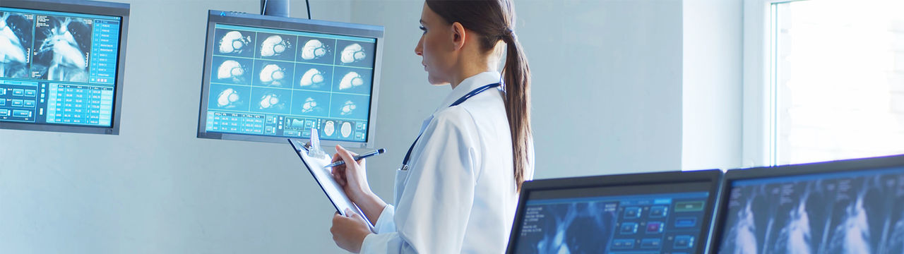Female hospital worker analyzing medical scans on digital screens