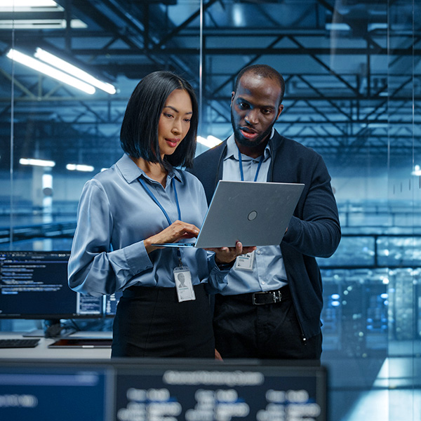 Engineers with computer in larger data center