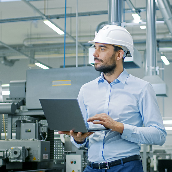 Engineer using laptop to monitor automation equipment.