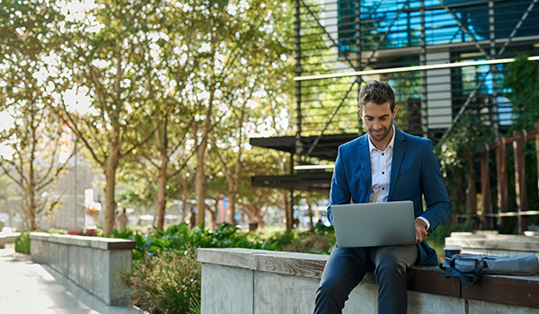 Professional man working on wireless computer outside office building.