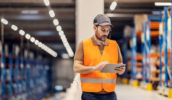 Warehouse worker tracking shipment using wireless device technology.