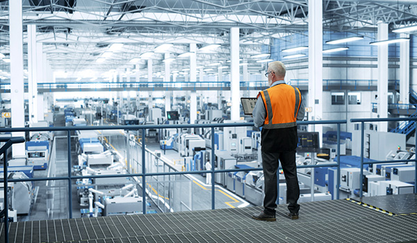 Engineer monitoring automation equipment on wireless device.